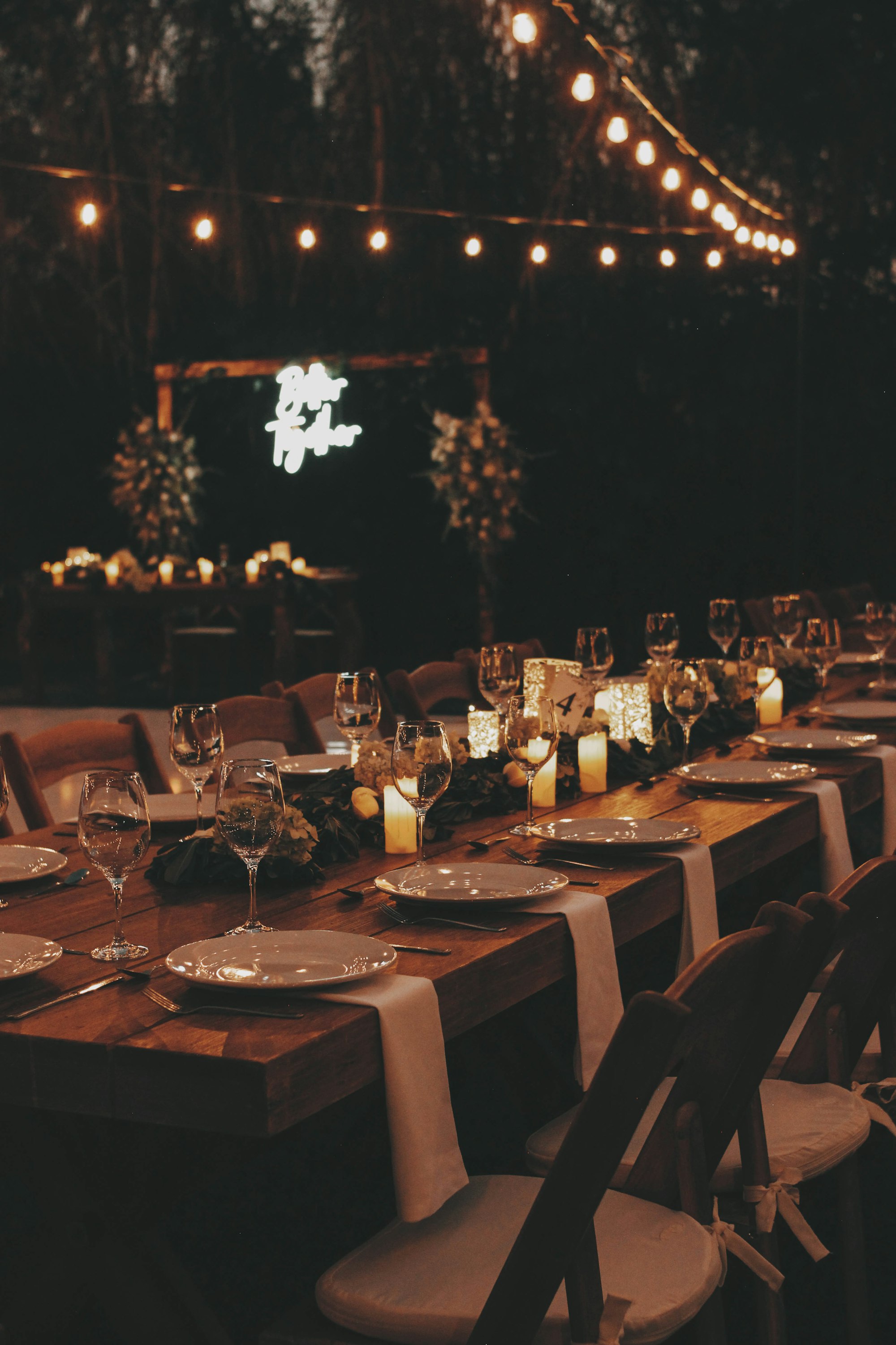Mesa larga de boda de noche con velas y luces, ambiente para resopón