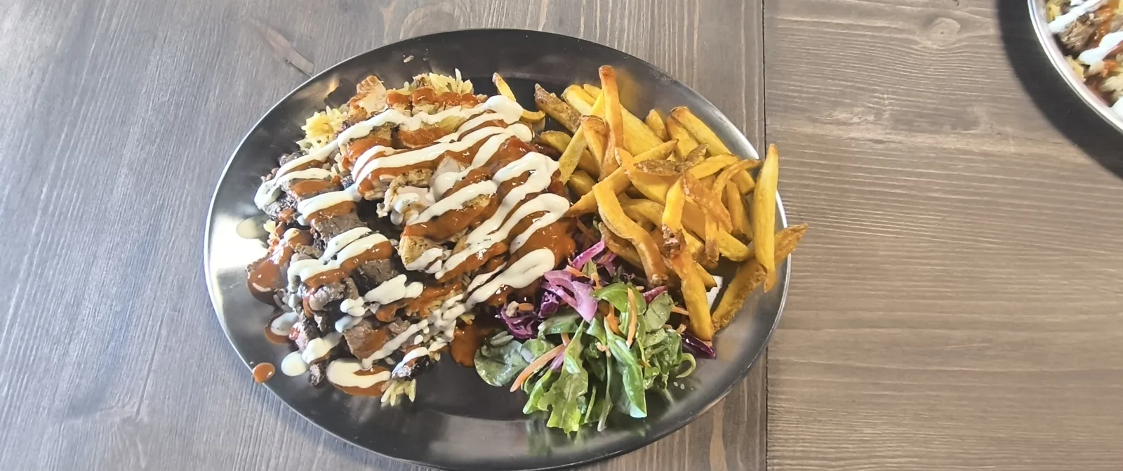 Plato de carne con ensalada, patatas y salsas